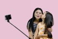 Mother and her daughter are making a selfie on smartphone using the stick. Royalty Free Stock Photo