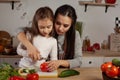 Mother and her daughter are making a vegetable salad and having fun at the kitchen. Royalty Free Stock Photo