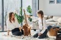 Mother with her daughter playing with dog. Cute little poodle puppy is indoors in the modern domestic room Royalty Free Stock Photo