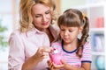 Mother and her daughter putting coins into piggy Royalty Free Stock Photo