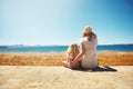 Mother and her daughter sitting on the seashore Royalty Free Stock Photo