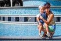 Mother in her fourties hugging her infant child outdoors in a park in a sunny day