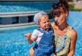 Mother in her fourties hugging her infant child outdoors in a park in a sunny day