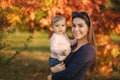 Mother with her little baby girl stand in front of red tree. Autumn park Royalty Free Stock Photo