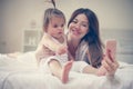 Mother with her little baby having fun in the bed. Royalty Free Stock Photo