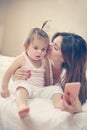 Mother with her little baby having fun in the bed. Using smart p Royalty Free Stock Photo