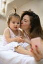 Mother with her little baby having fun in the bed. Using smart p Royalty Free Stock Photo