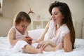 Mother with her little baby having fun in the bed. Using smart p Royalty Free Stock Photo