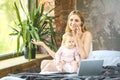 Mother and her little baby at home. Mother with her baby watching something on laptop. Working home. Using phone Royalty Free Stock Photo