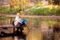 Happy young mother and her son spending time in the autumn park near the pond. Royalty Free Stock Photo