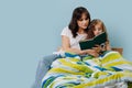 Mother and her little daughter are reading book in bed before going to sleep Royalty Free Stock Photo