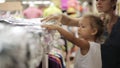 Mother with her little daughter selecting clothes at supermarket