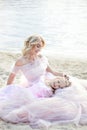 Mother and her little girl enjoying lake view and relaxing on the beach on a sunny day in beautiful dresses. A cheerful child and Royalty Free Stock Photo