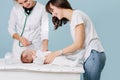 Mother with her little infant baby during a visit to a doctor over blue Royalty Free Stock Photo