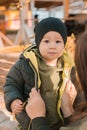 Mother with her little asian son in autumn park close-up. Woman zips up child jacket. Fall and motherhood concept