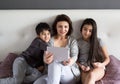 Mother and small kids having happy family time at home watching movie on tablet, taking a selfie, enjoying domestic life Royalty Free Stock Photo