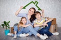 A mother with her son and daughter moves into a new apartment with things in cardboard boxes. The family creates a roof Royalty Free Stock Photo