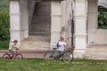 Mother and her son going with bicycles in the park, side view. Family spending active vocations in the summer.