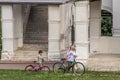 Mother and her son going with bicycles in the park, side view. Family spending active vocations in the summer.