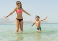 Mother and her son playing and running on the beach. Concept of friendly family Royalty Free Stock Photo