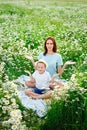 A mother and her son are resting in a field of chamomile flowers. Meditation in the midst of a blooming field. Relaxation and