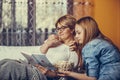 Mother and her teenage daughter are reading interesting book and eating popcorn while sitting on the couch Royalty Free Stock Photo