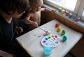 Mother and her toddler blond son dyeing Easter eggs together at home