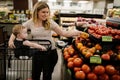 Mother and her toddler daughter buying organic tomatoes at the grocery store Royalty Free Stock Photo