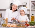 Mother and her young daughter in uniform are satisfied of ready salad Royalty Free Stock Photo