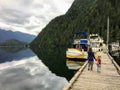 A mother and her young 5 year old daughter holding hands walking along the dock towards their boat.