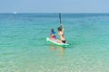 Mother and his adorable little daughter sitting on stand up board having fun during summer beach vacation Royalty Free Stock Photo