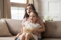 Mother hold daughter on lap watching movie feels shocked