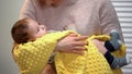 Mother holding adorable newborn, singing lullaby to calm baby, happy motherhood