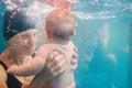 Mother holding baby dive. Diving baby, mother in paddling pool. Young mother, swimming instructor and happy little girl under Royalty Free Stock Photo