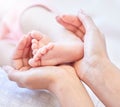 Mother holding baby feet. Closeup of tiny newborn baby feet held by a parent. Small baby toes. Little baby lying on a Royalty Free Stock Photo