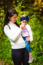 Mother holding baby girl sniffing a flower in forest Royalty Free Stock Photo