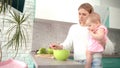 Mother holding baby on hands in kitchen. Mom with kid prepare dinner Royalty Free Stock Photo