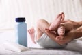 Mother holding baby`s legs on bed, closeup