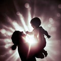 Mother holding a Baby Silhouette with sunlight flare shining from background.