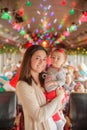 Mother holding beautiful baby girl with colorful Christmas lights in the background on train or bus Royalty Free Stock Photo