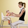Mother holding bottle for baby in highchair