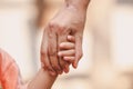 Mother holding a child`s hand on blurred bokeh background.