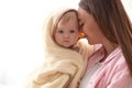 Mother holding cute little baby wrapped with hooded towel after bath on light background, closeup Royalty Free Stock Photo