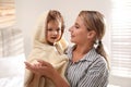 Mother holding cute little baby wrapped with hooded towel after bath indoors Royalty Free Stock Photo