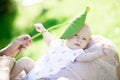 Mother holding cute newborn baby boy on the lap and playing with green leaf Royalty Free Stock Photo