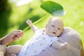 Mother holding cute newborn baby boy on the lap and playing with green leaf Royalty Free Stock Photo