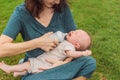 Mother holding and feeding baby from milk bottle in the park. Portrait of cute newborn baby being fed by her mother Royalty Free Stock Photo