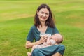 Mother holding and feeding baby from milk bottle in the park. Portrait of cute newborn baby being fed by her mother Royalty Free Stock Photo