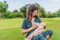 Mother holding and feeding baby from milk bottle in the park. Portrait of cute newborn baby being fed by her mother Royalty Free Stock Photo