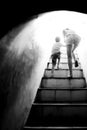 Mother holding hand her son walking up the stairs to bright sun light at the end of dark tunnel Royalty Free Stock Photo